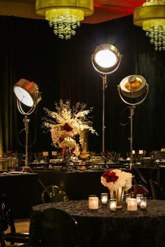 a table topped with lots of candles and flowers next to two spotlights on top of tables