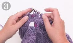 two hands are knitting the ends of a purple knitted bag