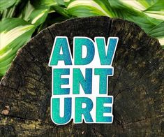 the word adventure is placed on top of a piece of wood