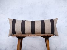 a black and white striped pillow sitting on top of a wooden stool next to a wall