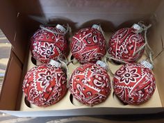 six red and white ornaments in a cardboard box