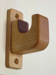 a wooden hook on the wall with a purple object hanging from it's side