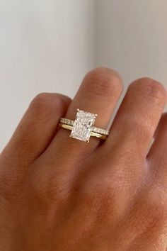 a woman's hand with a diamond ring on top of her finger and an engagement band