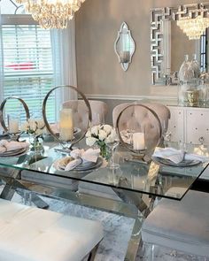 a glass dining table with chairs and candles