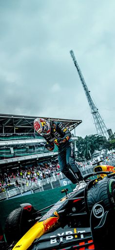 a man riding on the back of a red bull racing car in front of a crowd