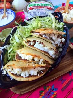 some tacos are sitting on a cutting board and ready to be eaten with toppings