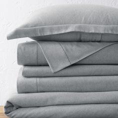 a stack of gray sheets and pillows on a wooden table