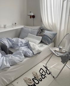 a white couch covered in sheets and pillows with a laptop on it's side