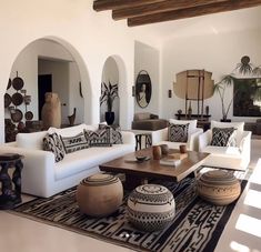 a living room filled with white furniture and lots of pillows on top of a rug