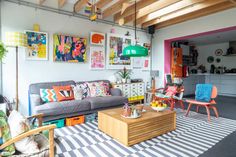 a living room filled with lots of furniture and colorful art on the wall above it