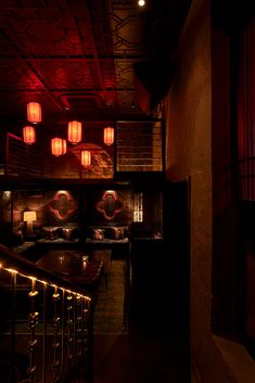 a dimly lit room with red lanterns hanging from the ceiling and stairs leading up to it