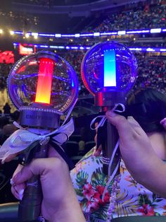 two people holding up lights in front of an audience at a convention or concert hall