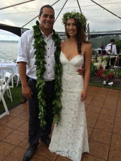 a man and woman standing next to each other in front of a tent with flowers on it