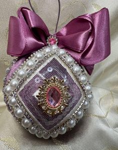 a purple ornament with pearls and a bow