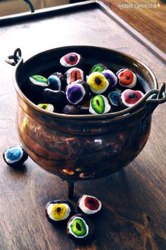 a metal bowl filled with lots of colorful glass beads on top of a wooden table