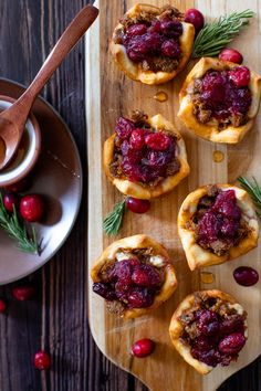 small cranberry and rosemary appetizers on a wooden platter next to a cup of tea