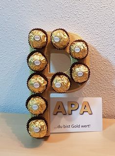 the letter p is made out of chocolates and wrapped in gold wrappers with a sign that says apa