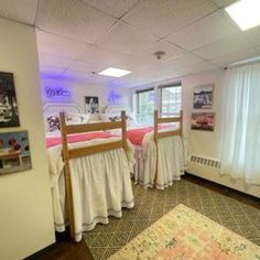 two bunk beds in a room with white curtains and pink blankets on the bedding