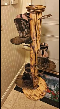 cowboy boots are stacked on top of a wooden pole in the corner of a room