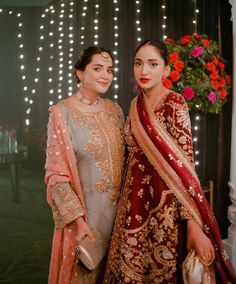 two women standing next to each other in front of a wall with lights on it