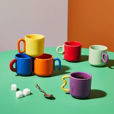 colorful cups and spoons sitting on a green table