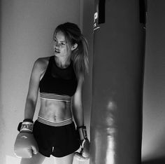 a woman standing next to a punching bag