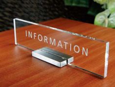 a clear acrylic sign sitting on top of a wooden table