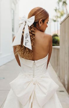 a woman in a white dress with a big bow on her back