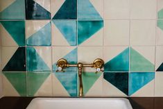 a white sink sitting under a bathroom faucet next to a tiled counter top