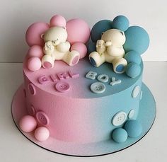 two teddy bears sitting on top of a pink and blue cake