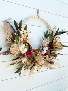 a wreath with dried flowers and leaves hanging on a wall