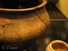 an old vase sitting on top of a table next to a small bowl filled with water