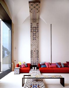 a living room filled with lots of red couches next to a tall white wall