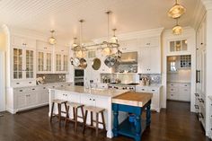 a large kitchen with white cabinets and wooden floors is pictured in this image, there are three stools at the center of the island