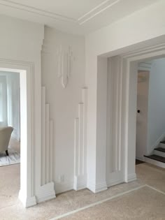 an empty living room with white walls and columns on the wall, carpeted floor