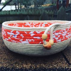 an orange and white basket sitting on the ground