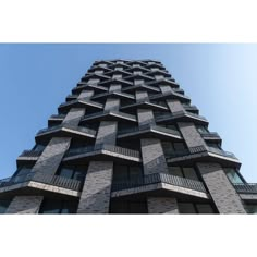 a tall building with balconies on the top and bottom floors, against a blue sky