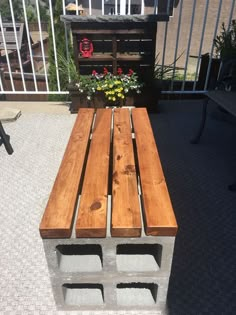 a wooden bench sitting on top of a patio next to a planter filled with flowers