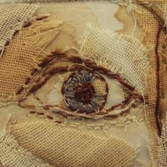 an eye made out of burlap and rope on fabric with stitchs around it