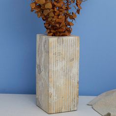 a vase filled with lots of branches on top of a white table next to a blue wall