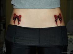 a woman's lower back tattoo with red bows on her belly and the bottom part of her stomach