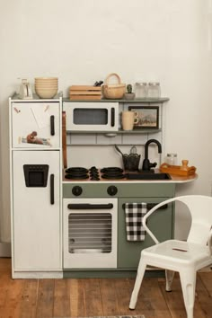 a small kitchen with an oven, stove and chair in the middle of the room