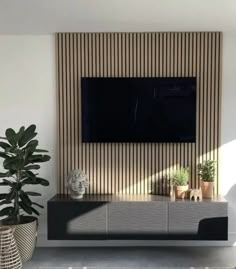 a living room with a large flat screen tv on the wall and two planters next to it