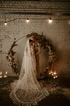 a bride and groom standing in front of a wedding arch with candles on the floor