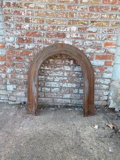 an arched wooden door in front of a brick wall with dirt on the ground below