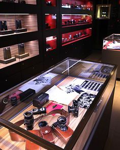 a display case filled with lots of different types of cameras and other items on top of a wooden table