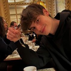 a young man sitting at a table eating food