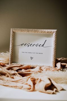 a white framed sign sitting on top of a bed next to a pile of blankets