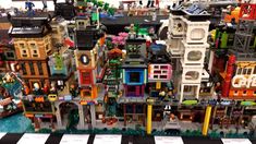 a large lego city with lots of buildings and people on it's sides, in front of a black and white checkered table cloth