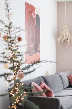 a living room with a christmas tree in the corner and decorations hanging on the wall